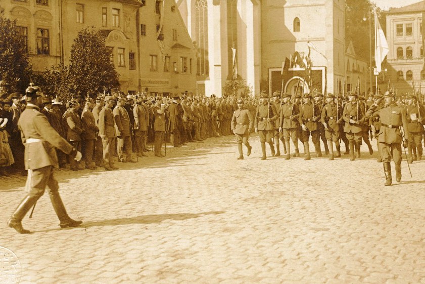 Militärparade am Oberen Hauptplatz vor dem auf Höhe der Bortenschlager-Brauerei stehenden Kriegerdenkmal von 1902 unter starker Anteilnahme der Bevölkerung. Das Bild entstand um das Jahr 1916. Fotos: Stadtarchiv