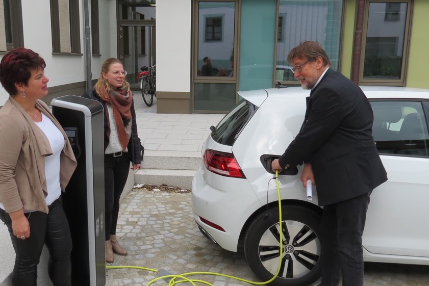 Landrat Martin Wolf (CSU) macht den E-Tankwart. Das Auto von Sandra Schmeller (links) wurde beim ersten offiziellen Ladevorgang im Innenhof des Landratsamts mit Strom versorgt. Mit auf dem Bild: Monika Meier von der Servicestelle der Kreisbehörde. Foto: Rottler