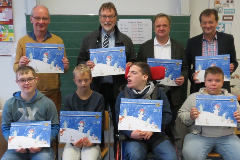 Landrat Martin Wolf (hinten, Zweiter von links) mit dem stellvertretenden Schulleiter Erich Noack (links), dem Vorsitzenden des Fördervereins "Hilfe für das behinderte Kind", Anton Steinberger (Dritter von links), sowie dem Geschäftsführer des Vereins, Franz Schreyer (rechts), bei der Übergabe der Advents-Kalender an einige Kinder. Foto: Landratsamt / Brummer